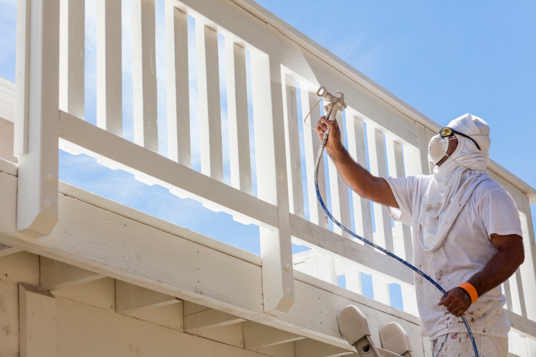 G2 Painting and Roofing employee painting a deck of a home