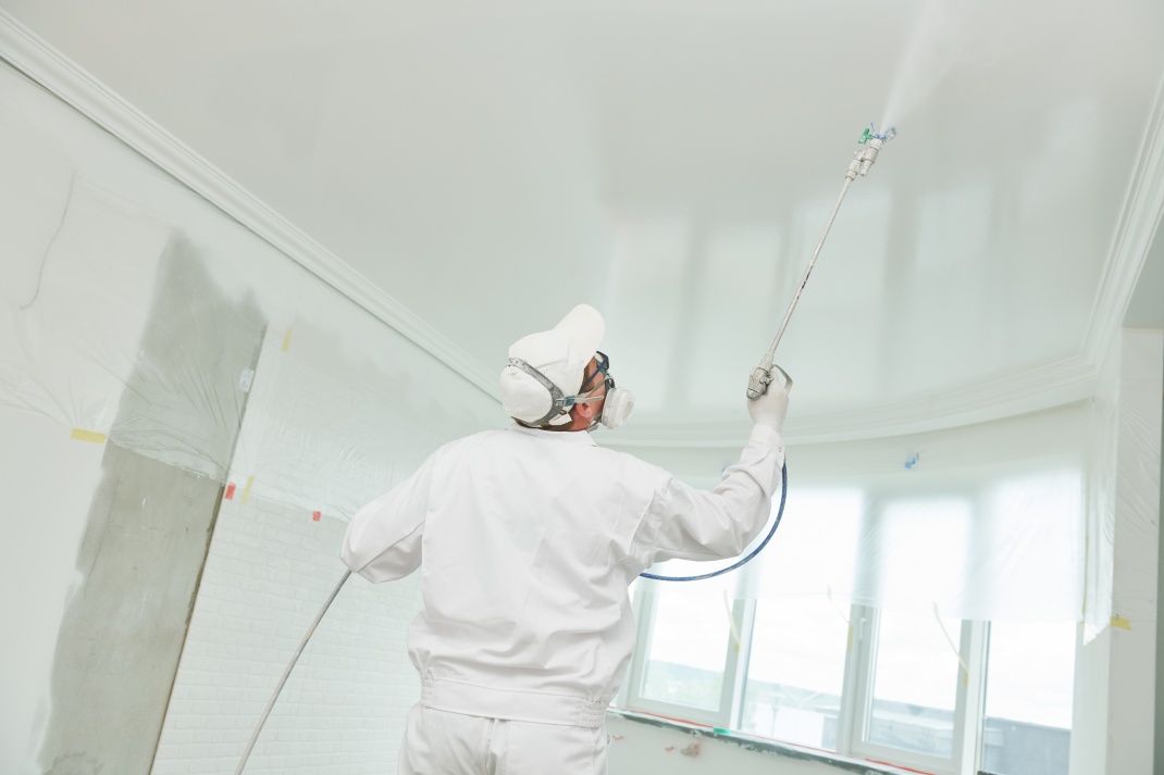 G2 Painter worker with airless painting sprayer covering ceiling